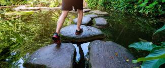 A person walking on stone steps on an outdoor pond.